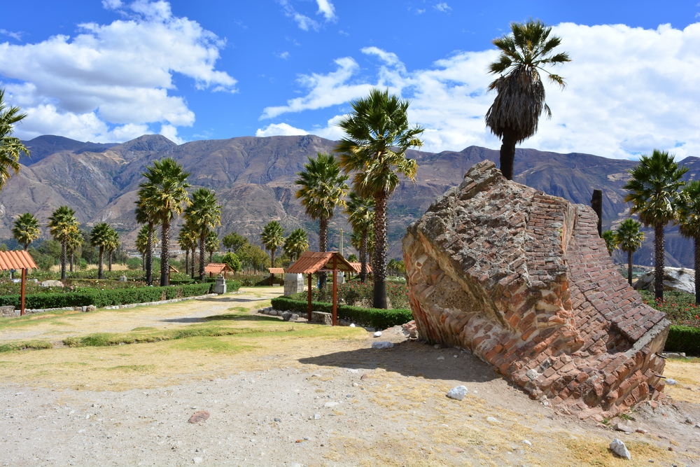Gorgeous palm trees next to a rock and walking path with mountains in the background in one of the best places to visit in Peru, Huaraz