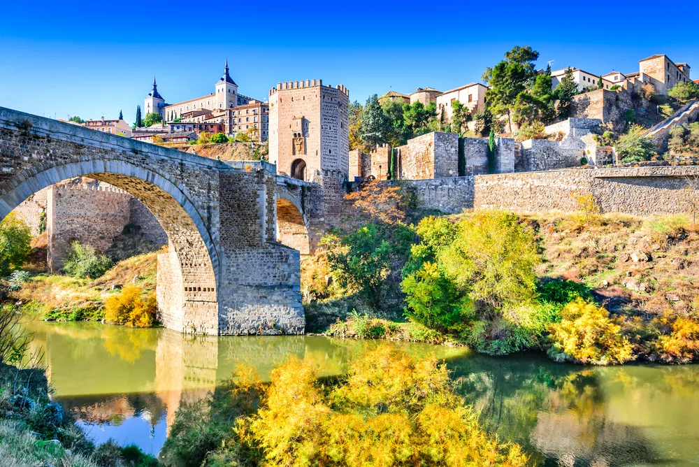 Arch bridge in Toledo spanning the Tagus River looking like it's taken straight out of a fairy tale book for a roundup of the best places to visit in Spain