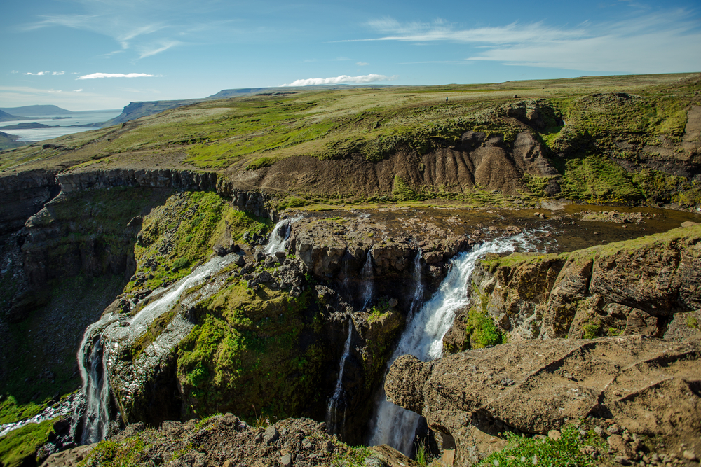 Water flowing down the Glymur Waterfall, a top pick for the best places to visit in Iceland, with green moss on the rocks for as far as the eye can see