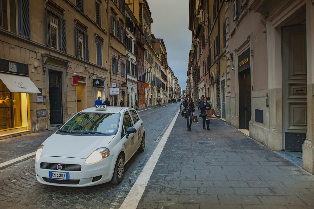 Taxi in the street of Rome pictured with people walking along the Via Del Babuino for a roundup of the best hotels in Rome