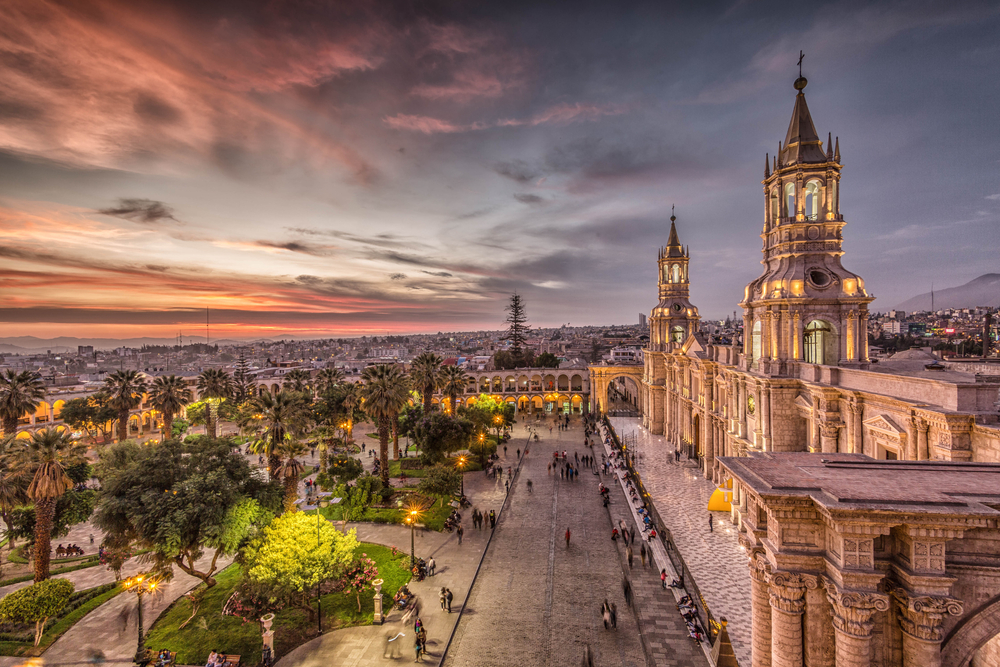 Sunset over Arequipa, a colonial-style town in Peru, pictured with a few people strolling through the gardens and walking paths below