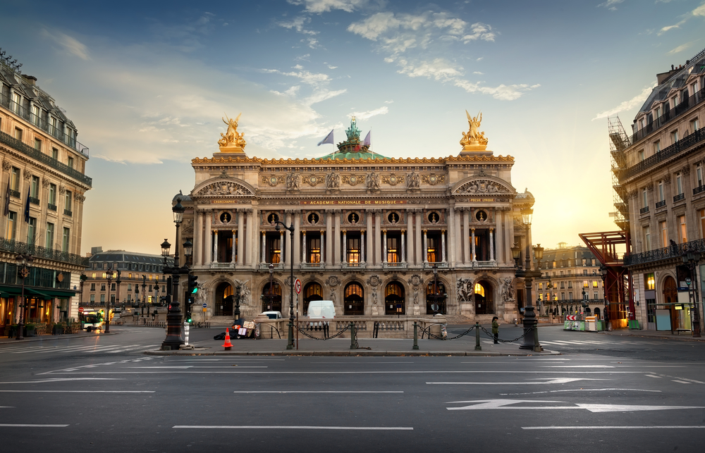 Palais Garnier pictured from the street with no cars in sight and a still dusk sky behind it