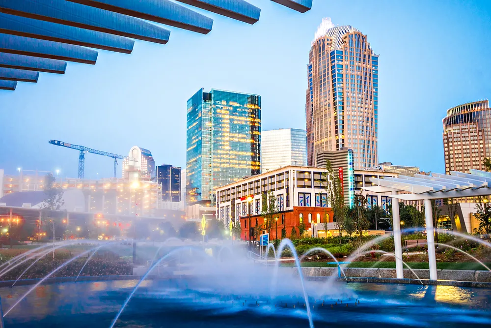 Modern skyscraper pictured in the background of a splash pad or fountain in a artsy part of downtown Charlotte