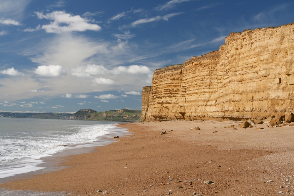 Dirt cliffs tower over the beach of the Jurassic Coast, one of the best places to visit on a trip to England