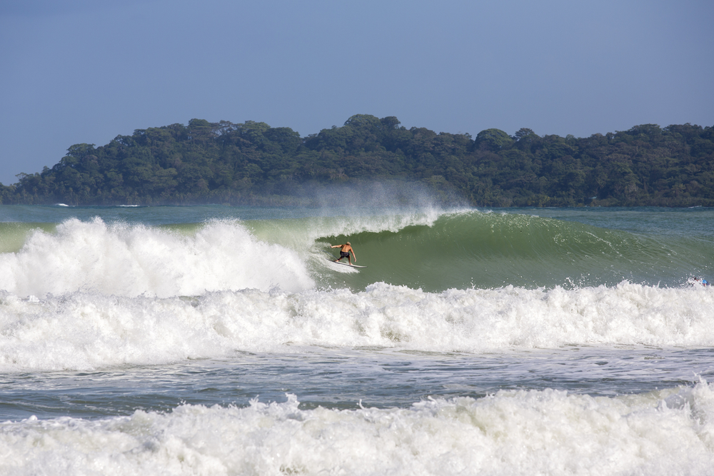 Man surfing on the Sunset Coast, one of the best places to visit in Panama, with large waves crashing on the coast