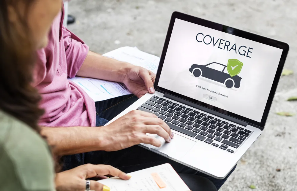 Woman uses laptop computer showing car insurance coverage to help people decide should you get insurance on a rental car