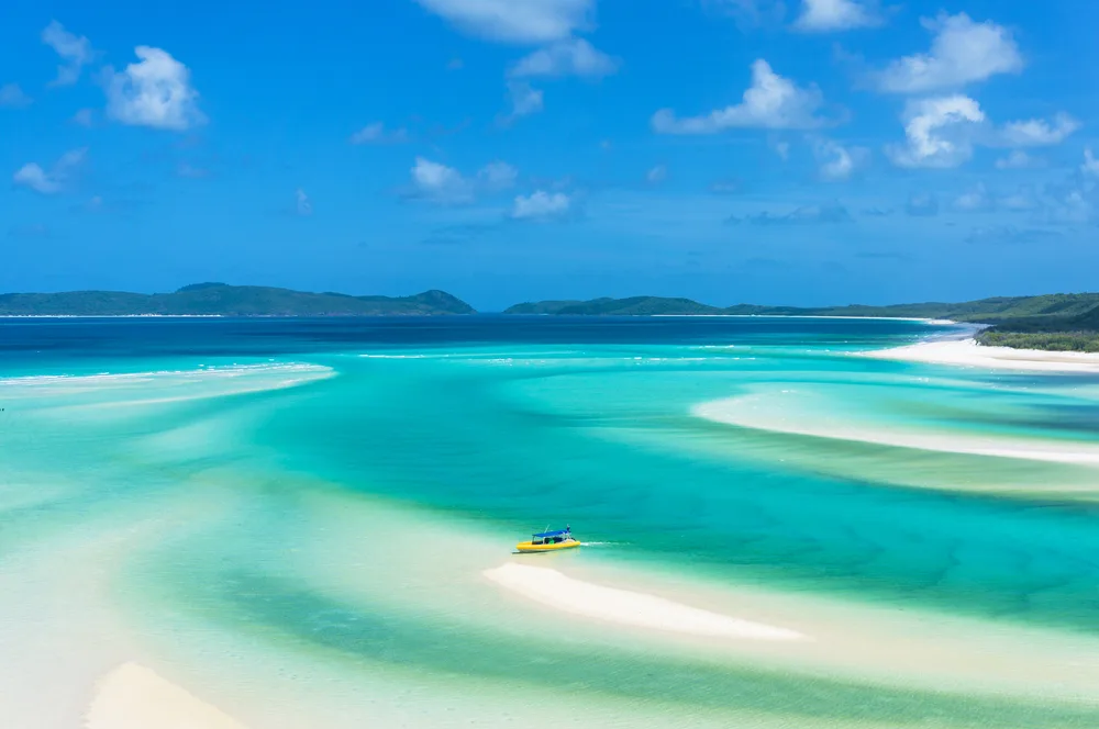 Picturesque blue lagoon with giant white sandbars pictured under a clear blue sky in the Whitsundays, one of the best places to visit in Australia