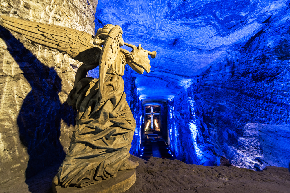 Walkway down the stunning Salt Cathedral pictured with its blue lights and an angel statue next to the entrance