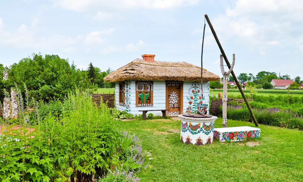 Colorful gypsie village of Zalipie with a colorful well and a small boho-style home in the middle of a field of flowers