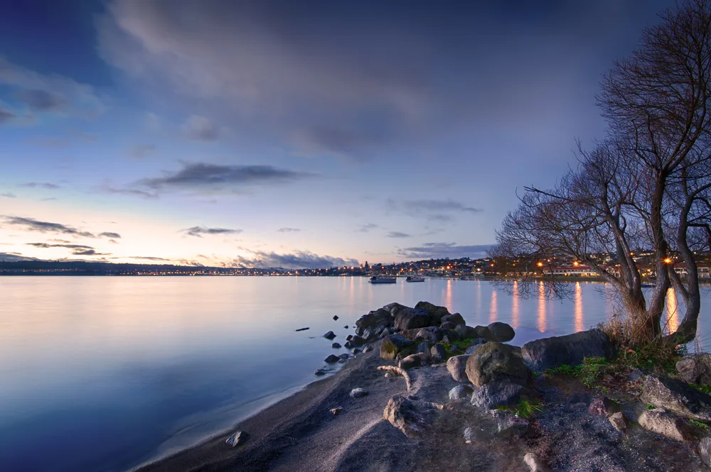 Night view of the amazing lake town of Taupo, one of the best places to visit in New Zealand, pictured with the sun setting overhead