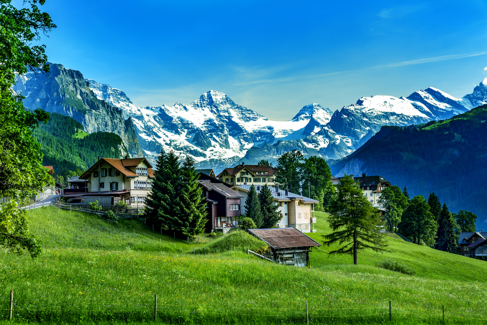 Small homes in the Swiss town of Jungfraujoch, one of the best places to visit in Switzerland, pictured from the grass