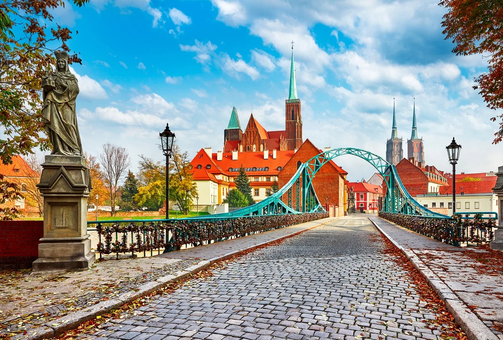 Pretty fall day in Wroclaw, a top pick for Poland's best places to visit, with a green structure over the stone path and a church in the background