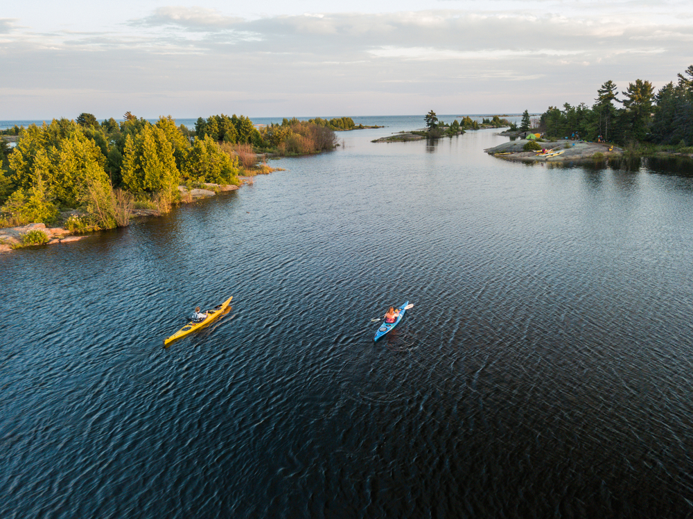 A couple with blue and white kayaks pictured paddling along the lake