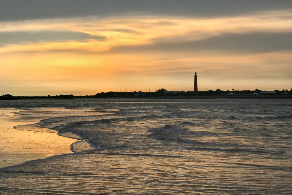Ocean view with Ponce Inlet and lighthouse in the distance at sunset in New Smyrna Beach, one of the best beaches in Florida