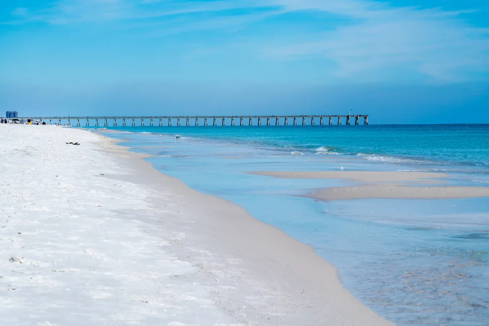 Pensacola Beach, one of the best beaches in Florida, on an uncrowded day with blue skies and pier jutting out into the water 