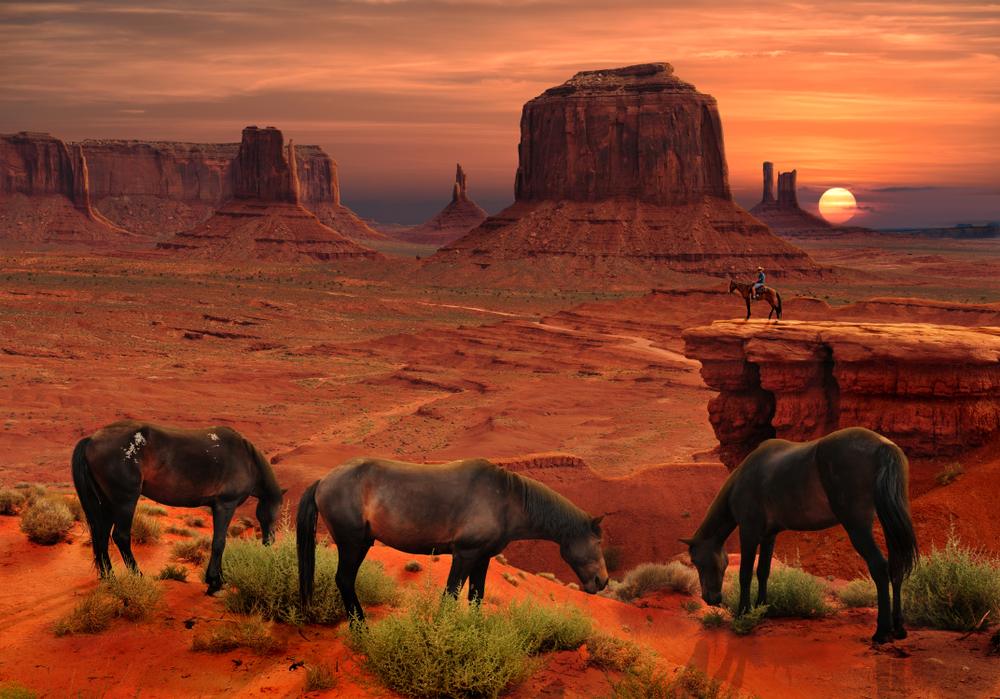 Horses eating at John Ford's Point Overlook in Monument Valley during a colorful sunset, one of the best places to visit in February