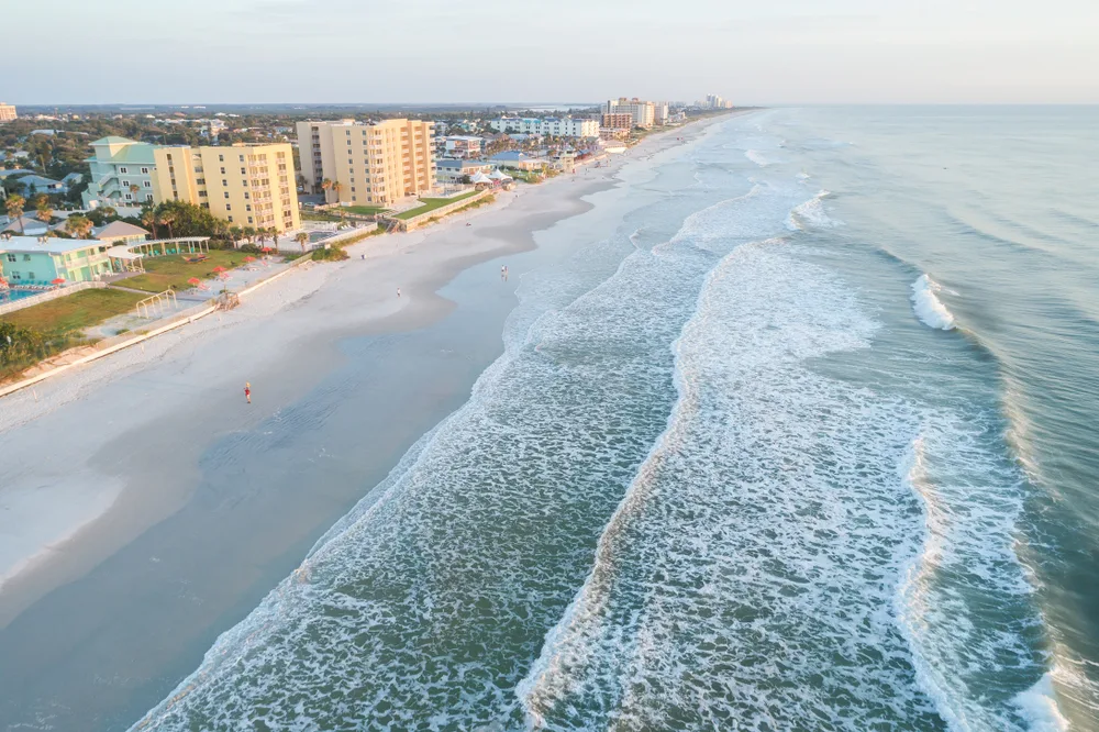 Aerial view of New Smyrna Beach with waves crashing on shore at sunset to show one of the top beaches in Florida