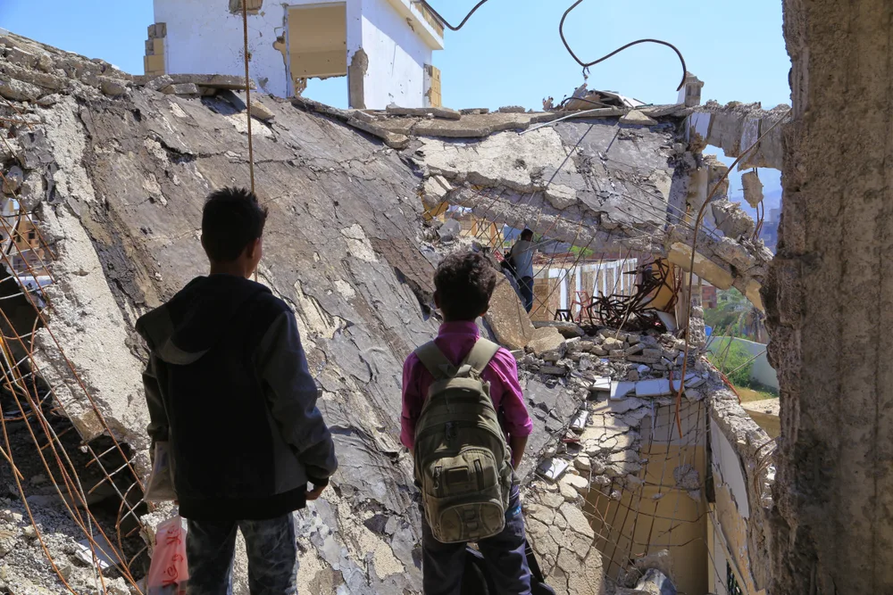 Poor kids stand in the window of a bombed-out school for a piece titled Is Yemen Safe to Visit