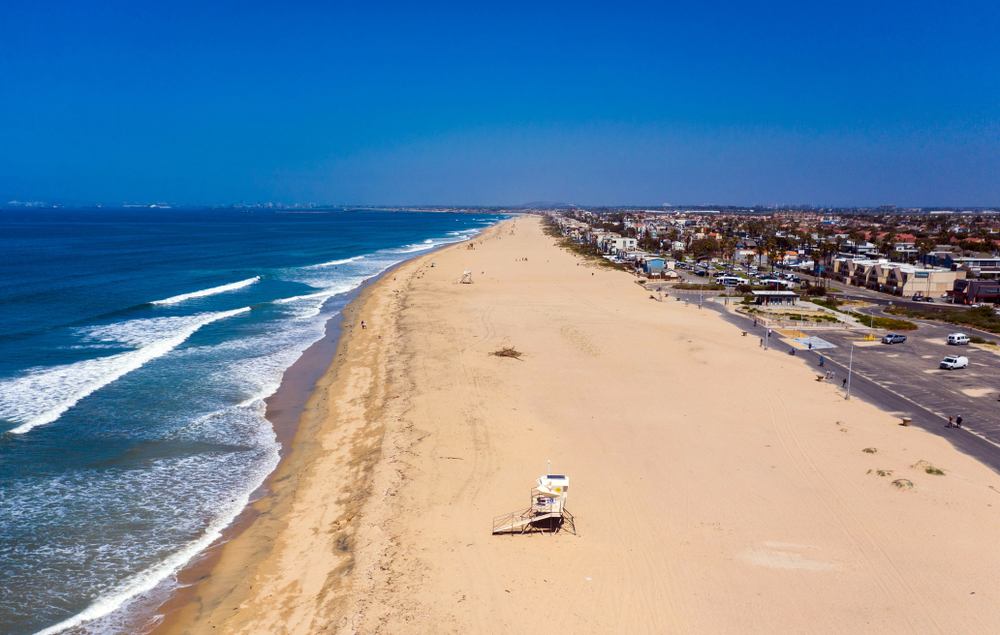 Aerial view of Bolsa Chica State Beach during the afternoon with nearly empty shoreline, showing one of the best beaches in California