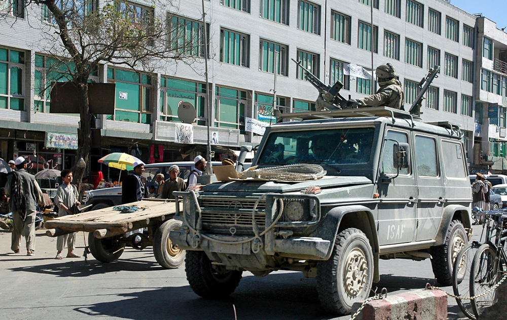Military vehicle driving by the camera in Kabul to illustrate that the city is not safe to visit