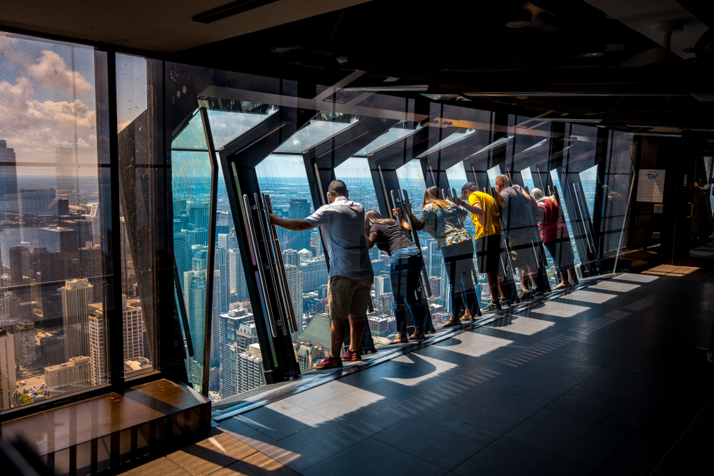 People at the 360 observation deck, one of Chicago's best places to visit, looking down through the glass