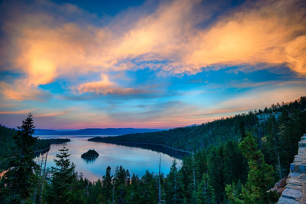 Aerial view of Lake Tahoe at dusk with evergreen trees surrounding it as one of the best places to visit during June