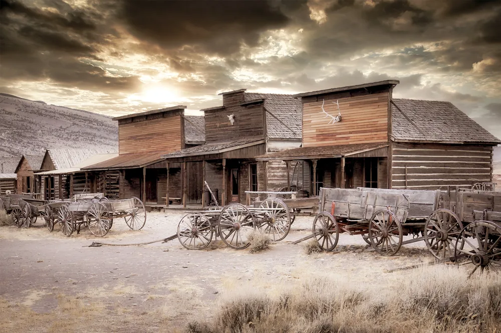 Old Trail Town in Cody, a top pick for must-visit places in Wyoming, pictured with abandoned wooden buildings alongside old horse-drawn carts