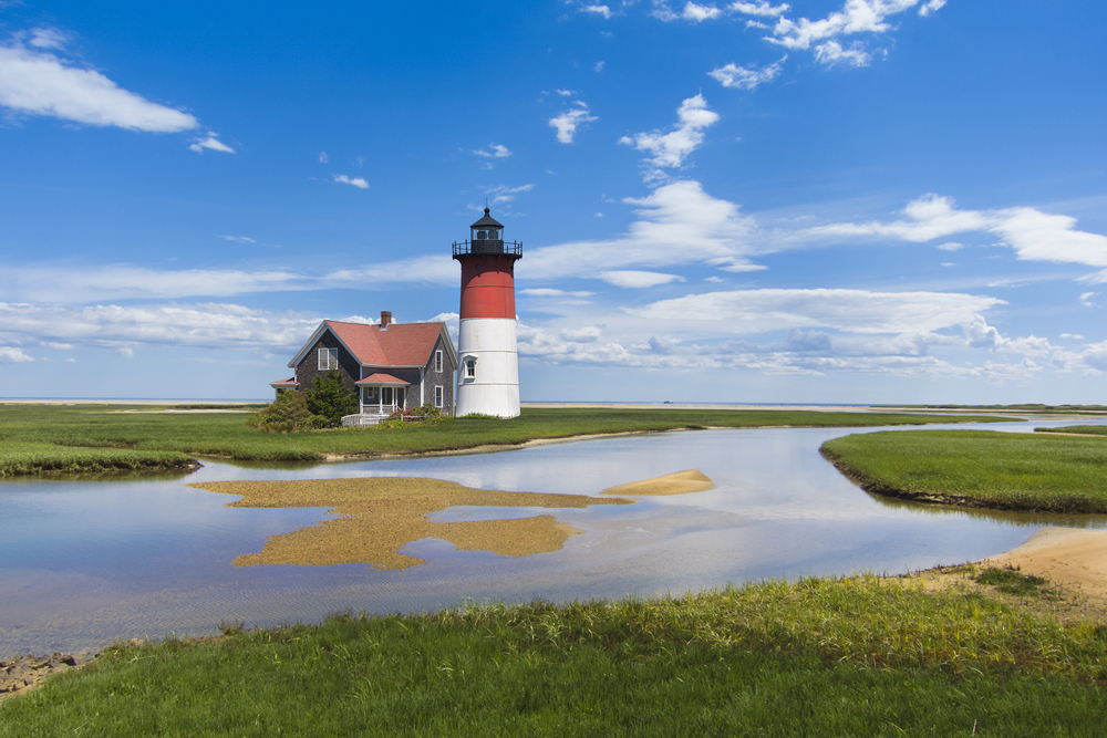 Cape Cod lighthouse and house off the coast on a nice day for a piece showing the 12 best places to visit in June