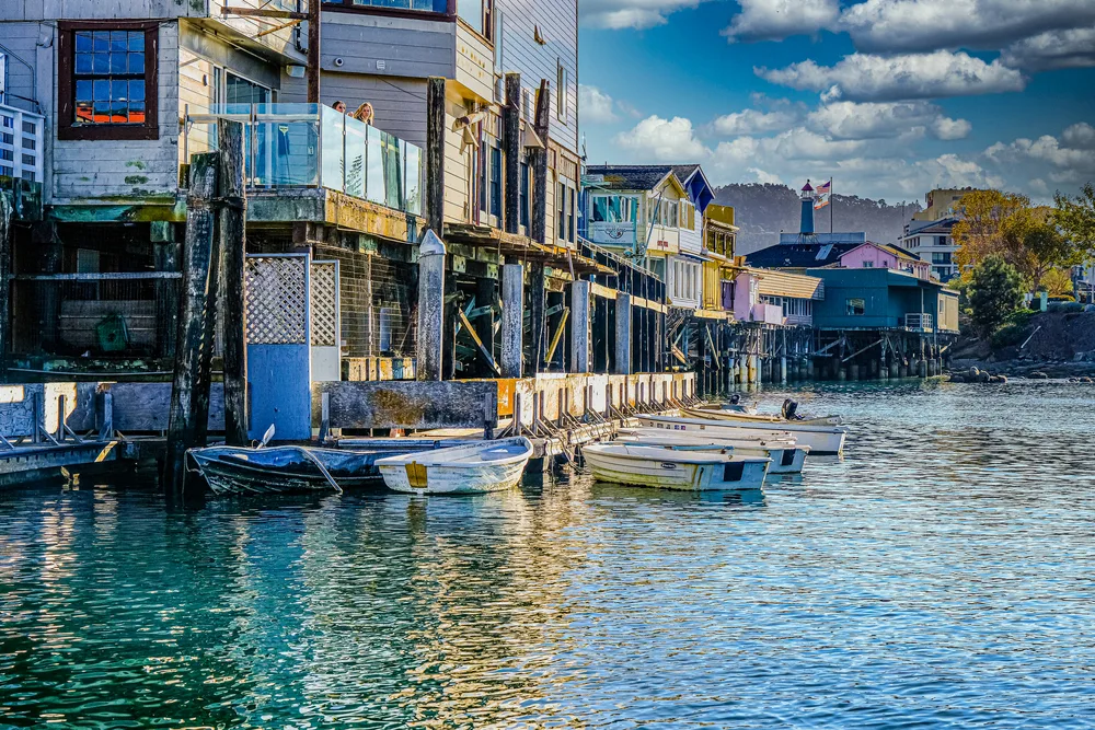 Idyllic view of the pier in Monterey Bay, one of the best areas to stay in California Wine Country, with colorful rowboats floating on the water