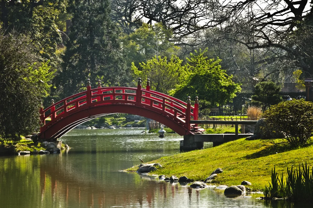 Walking path and bridge over a small pond pictured during the best time to visit Buenos Aires with few people in the otherwise serene scene