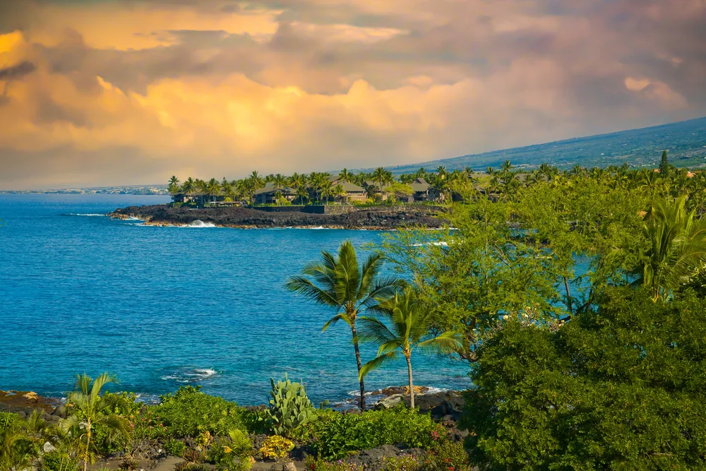 View of the Kailua Kona coast at sunset on a cloudy warm day during the overall best time to visit Kona