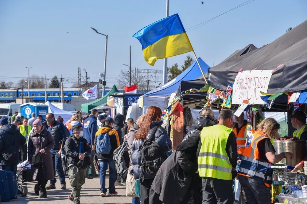 Refugees at the Poland/Ukraine border (an area to avoid when asking "Is Poland Safe to Visit"), with Ukrainian flags flying high above