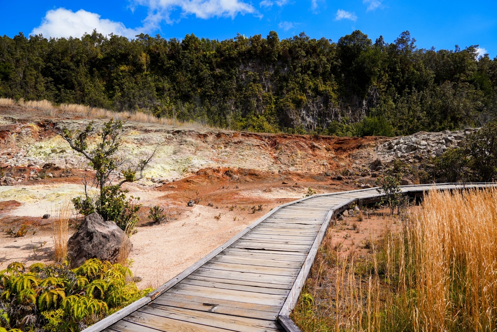 For a piece titled Is Kilauea Safe to Visit, a wooden boardwalk pictured running along the marshes and sand in the national park