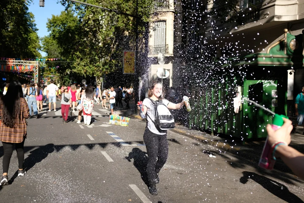 Smiling woman spraying foam all around the streets of Buenos Aires (during the worst time to visit) during Carnival