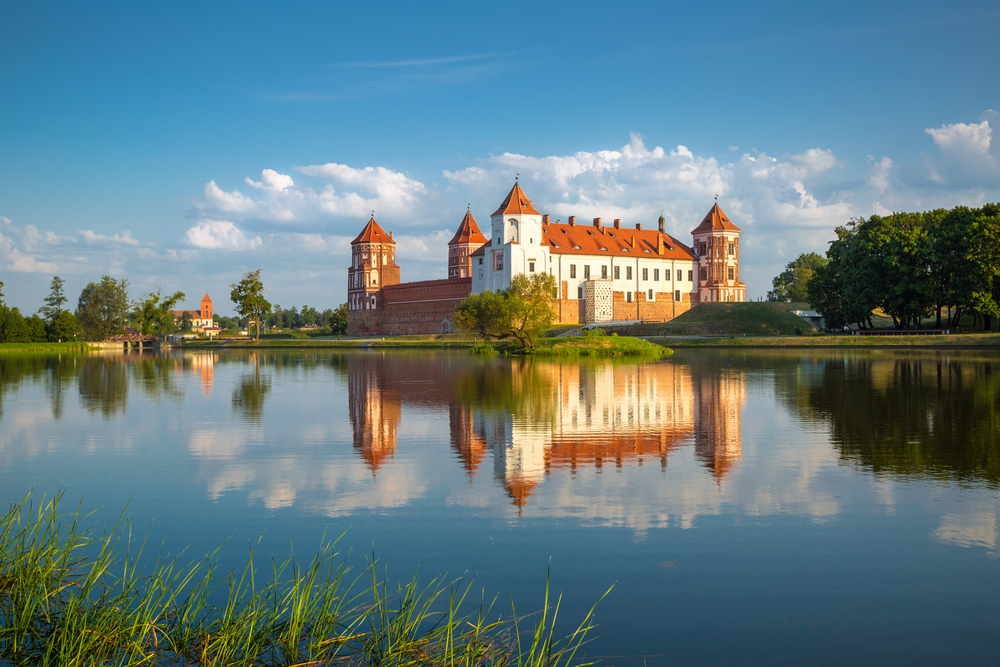 Mir Castle with reflection shown in the lake around it shows why you should visit Belarus