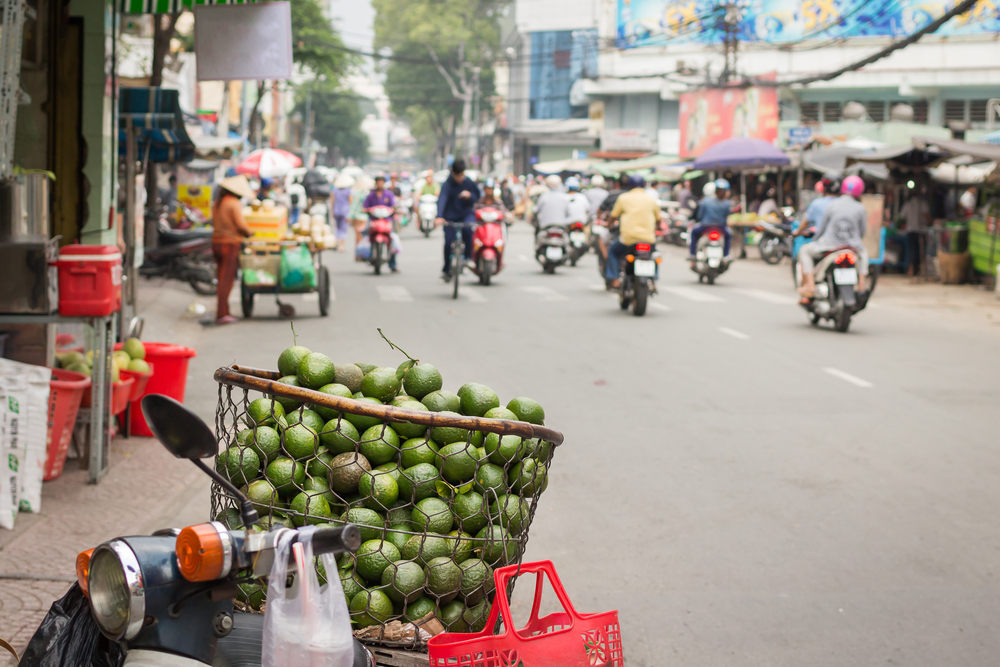 To illustrate some of the least safe areas in Vietnam, a photo of people riding mopeds in Ho Chi Minh, seen with a large basket of limes in the foreground