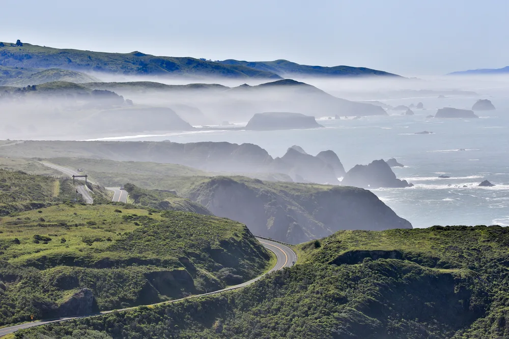 Gorgeous view of the cliffside town of Bodega Bay with fog rolling in off the ocean for a piece titled Where to Stay in California's Wine Country