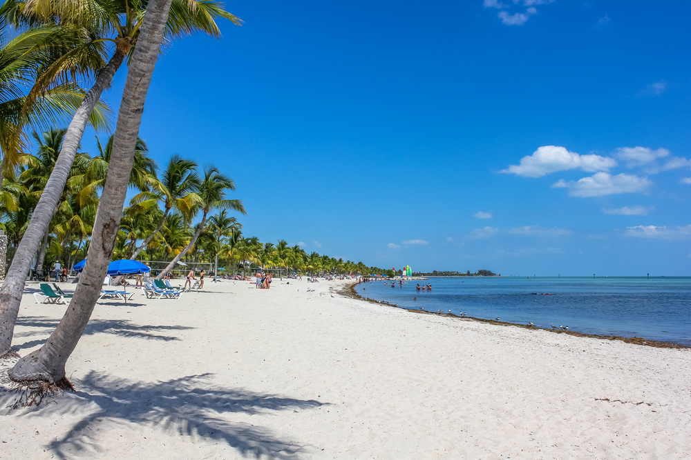 Smathers Beach in Key West is shown with tourists relaxing on a nice day as an example of the best beaches in the USA