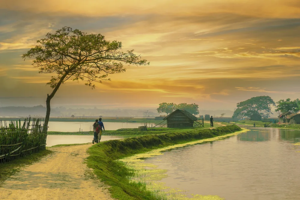 Small village outside the city with an elevated walking path between water pictured for a piece titled Is Bangladesh Safe to Visit