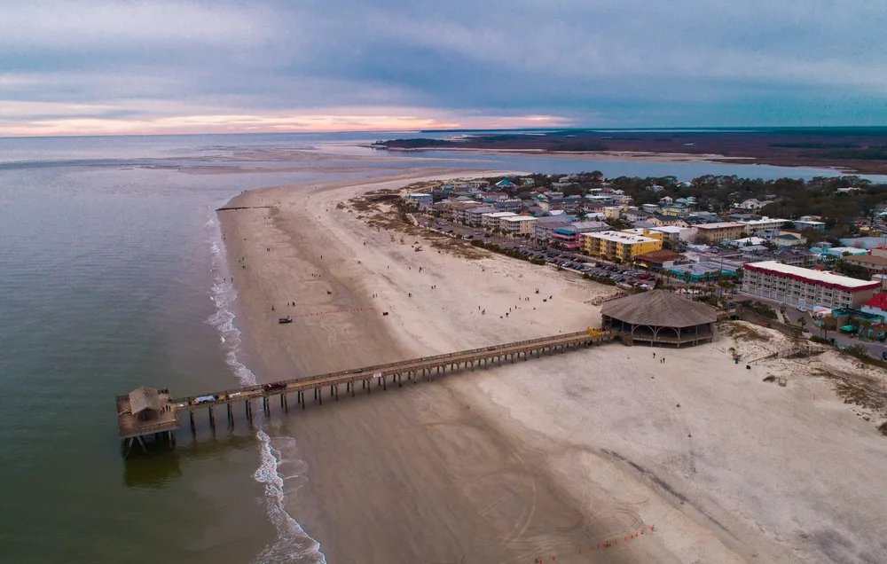 Resort and a giant boardwalk and wide beach seen at low tide in an aerial image of Tybee Island, one of Georgia's best places to visit