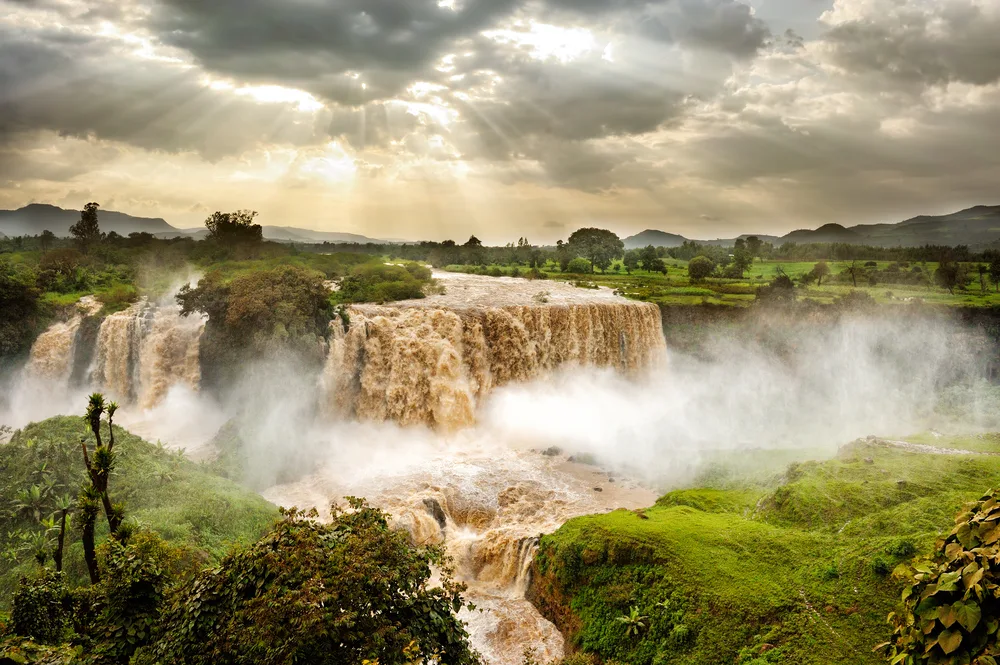 The Blue Nile Falls rushing on a nice day with clouds overhead during the overall best time to visit Ethiopia