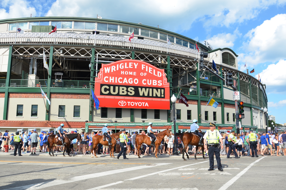 Exterior view of Wrigley Field pictured with clouds overhead and a sign that says Cubs Win!