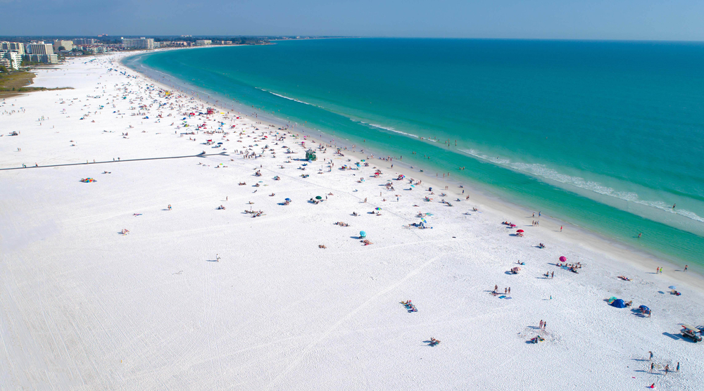 Drone aerial view of one of the best Florida beaches, Siesta Key Beach, with tourists relaxing on the shore on a summer day