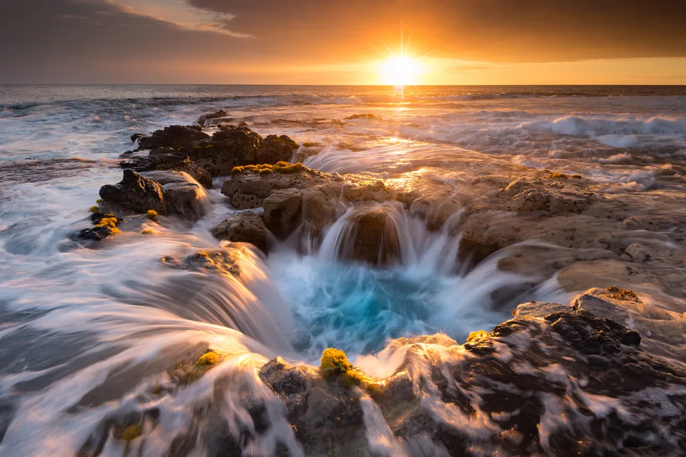 Pools of Paradise with rushing water shown at sunset in Kailua Kona during the cheapest time to visit Kona Hawaii