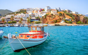 White and red boat floating on the water on the Agia Galini island pictured during the summer, the overall best time to visit Crete, Greece