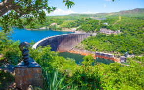 View from the top of the hill looking down at the Lake Kariba dam and the statue of nyami the river snake god for a piece titled Is Zimbabwe Safe to Visit