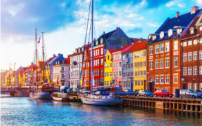 Sailboats moored on the river in front of colorful red, blue, and yellow homes in the Nyhavn Pier in Copenhagen during the overall best time to visit Scandinavia