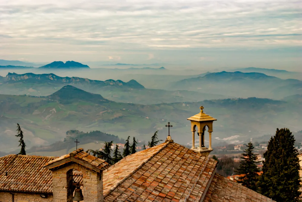 Aerial view looking out into the foggy hills around with cathedrals in focus during the least busy time to visit San Marino