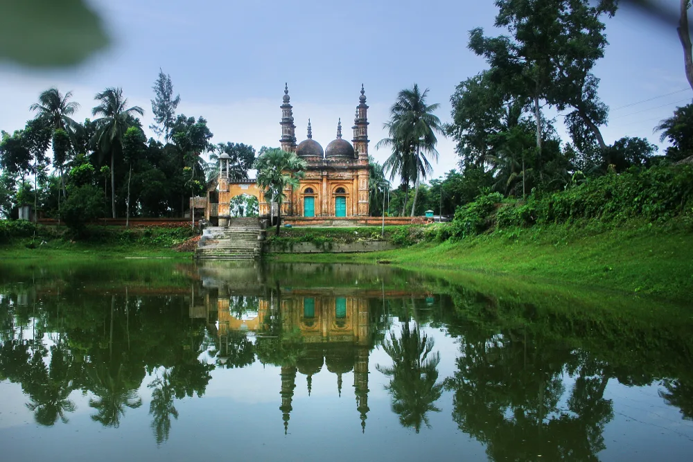 View across the pond at Tequila Jame Masjid in Satkhira on a beautiful day showing why you should visit Bangladesh