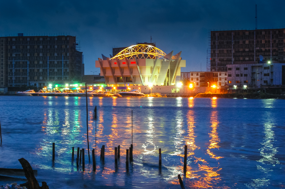 Photo of the Lagos skyline at dark with a convention center overlooking the water for a guide titled the best time to visit Nigeria